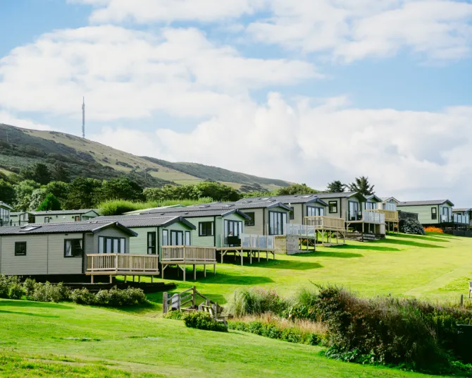 Static caravans and holiday lodges on a green hillside holiday park